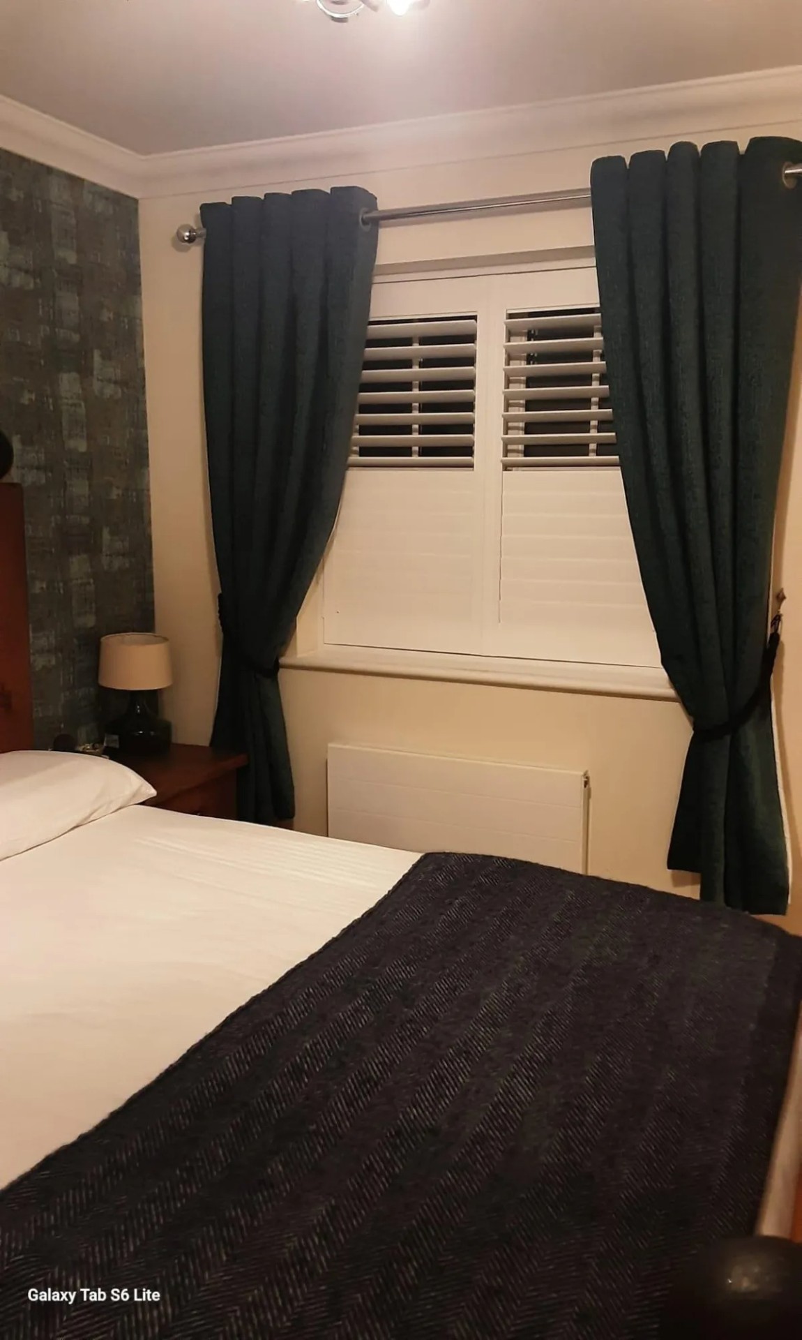 Dark teal curtains paired with plantation shutters in a bedroom