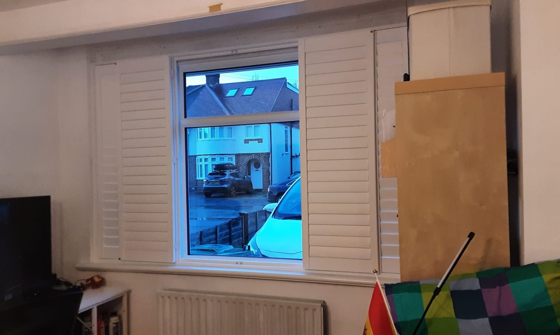 Full-height plantation shutters open on a street-facing window