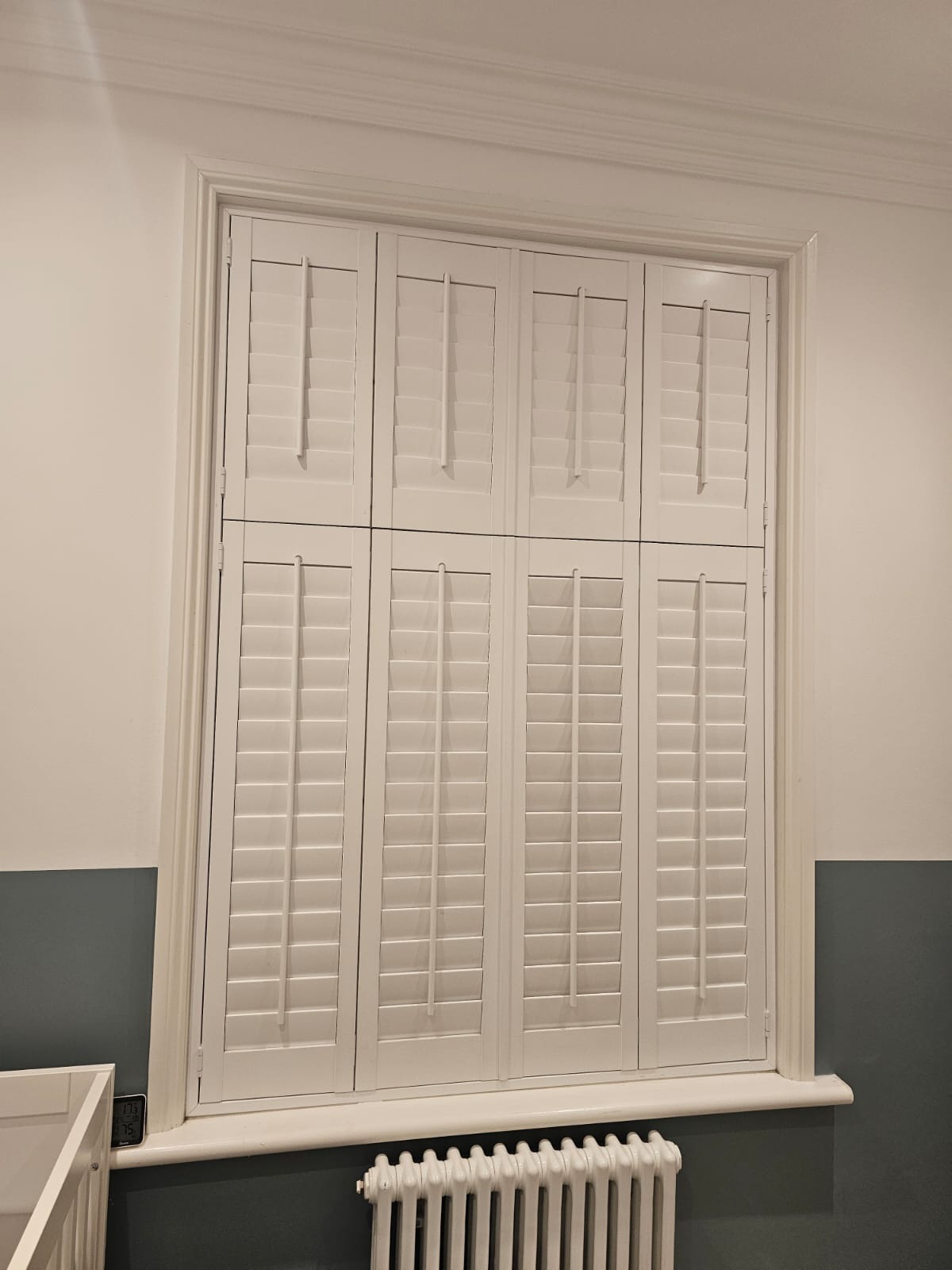 Bay window plantation shutters with blinds behind in a period bedroom