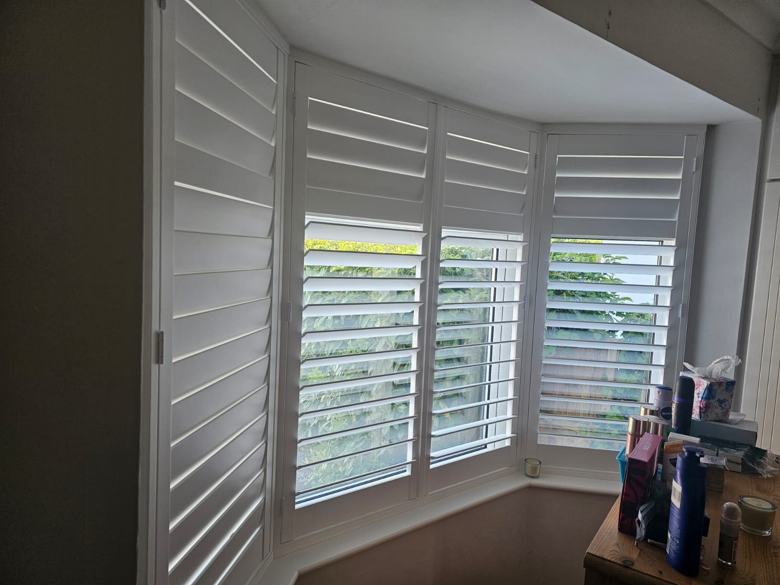 Bay window plantation shutters with louvres angled for garden view
